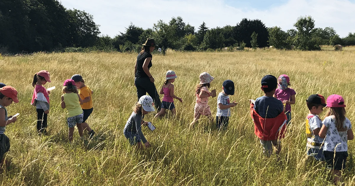 enfants courant dans un champ avec une animatrice