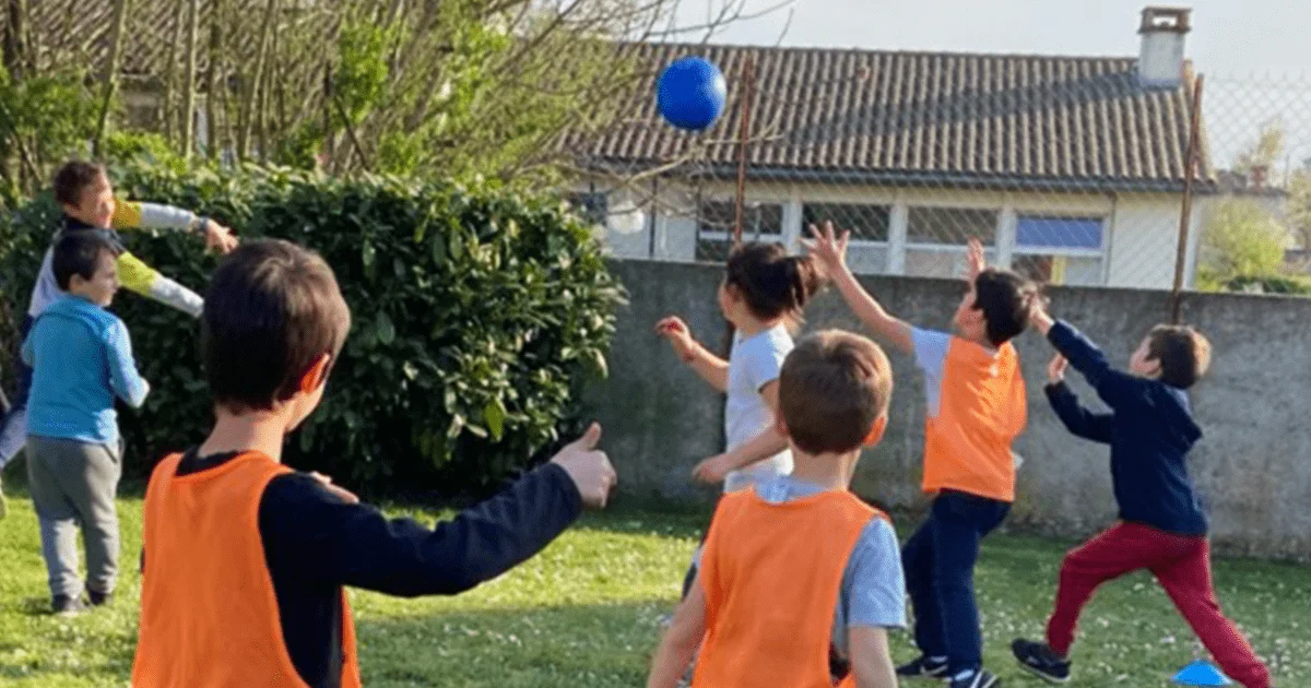 enfants portant des chasubles oranges jouant avec un ballon